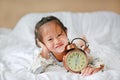 Happy beautiful girl with alarm clock on bed Royalty Free Stock Photo