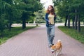 Cute girl walking with dog in green park holding smart phone smiling Royalty Free Stock Photo