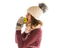 Cute girl in warm sweater, hat, scarf and mittens eating an apple Royalty Free Stock Photo