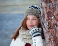 Cute Girl in warm winter clothes smiles flirtatiously during snowfall in front of a wooden barn with lots of snow falling from the Royalty Free Stock Photo