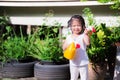 Cute girl was holding yellow watering can  smiling sweetly in garden of small tree in front of house. Children help with housework Royalty Free Stock Photo