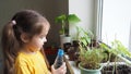 Cute girl watering seedlings on the windowsill first spring flowers. home interior and decoration. Child taking care of Royalty Free Stock Photo