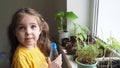 Cute girl watering seedlings on the windowsill first spring flowers. home interior and decoration. Child taking care of Royalty Free Stock Photo