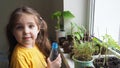 Cute girl watering seedlings on the windowsill first spring flowers. home interior and decoration. Child taking care of Royalty Free Stock Photo