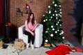 Cute girl wear on warm sweaters, black pants against new year tree with christmas decoration at studio