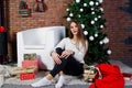 Cute girl wear on warm sweaters, black pants against new year tree with christmas decoration at studio