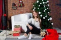 Cute girl wear on warm sweaters, black pants against new year tree with christmas decoration at studio