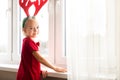 Cute girl wearing costume reindeer antlers, standing by the window.