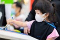 Cute girl wearing a 3D surgical face mask is taking art classes in classroom. Child make crafts with brushes painting water color Royalty Free Stock Photo