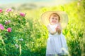 Cute girl wearing hat and white dress stand in the pink flower field of Sunn Hemp Crotalaria Juncea Royalty Free Stock Photo