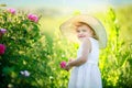 Cute girl wearing hat and white dress stand in the pink flower field of Sunn Hemp Crotalaria Juncea Royalty Free Stock Photo