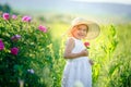 Cute girl wearing hat and white dress stand in the pink flower field of Sunn Hemp Crotalaria Juncea Royalty Free Stock Photo