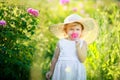 Cute girl wearing hat and white dress stand in the pink flower field of Sunn Hemp Crotalaria Juncea Royalty Free Stock Photo