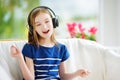 Cute girl wearing huge wireless headphones. Pretty child listening to the music. Schoolgirl having fun listening to kid`s songs at Royalty Free Stock Photo