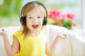 Cute girl wearing huge wireless headphones. Pretty child listening to the music. Schoolgirl having fun listening to kid`s songs at Royalty Free Stock Photo