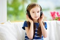 Cute girl wearing huge wireless headphones. Pretty child listening to the music. Schoolgirl having fun listening to kid`s songs at Royalty Free Stock Photo