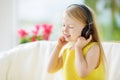 Cute girl wearing huge wireless headphones. Pretty child listening to the music. Schoolgirl having fun listening to kid`s songs at Royalty Free Stock Photo