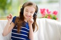 Cute girl wearing huge wireless headphones. Pretty child listening to the music. Schoolgirl having fun listening to kid`s songs at Royalty Free Stock Photo