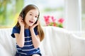 Cute girl wearing huge wireless headphones. Pretty child listening to the music. Schoolgirl having fun listening to kid`s songs at Royalty Free Stock Photo