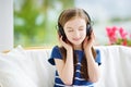 Cute girl wearing huge wireless headphones. Pretty child listening to the music. Schoolgirl having fun listening to kid`s songs at Royalty Free Stock Photo