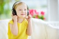 Cute girl wearing huge wireless headphones. Pretty child listening to the music. Schoolgirl having fun listening to kid`s songs at Royalty Free Stock Photo