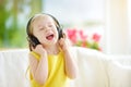 Cute girl wearing huge wireless headphones. Pretty child listening to the music. Schoolgirl having fun listening to kid`s songs at Royalty Free Stock Photo