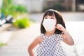 A cute girl wearing a white hygienic face mask stands looking up. Children are thinking and wondering what they see in the morning