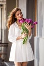 Cute girl in white dress and a beautiful bouquet of tulips.