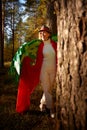 Cute girl in white dress, red scarf, male hat and green wings in nature landscape on sunny autumn. Model poses in green Royalty Free Stock Photo