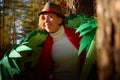 Cute girl in white dress, red scarf, male hat and green wings in nature landscape on sunny autumn. Model poses in green Royalty Free Stock Photo