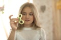 Cute girl in white shirt playing with green fidget spinner in bright room Royalty Free Stock Photo