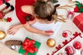 Unrecognisable girl writing letter to Santa on livingroom floor. Overhead view of a young girl writing her christmas wishlist. Royalty Free Stock Photo