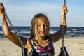 Cute girl 8-9 years old on swing against background of sea. Royalty Free Stock Photo