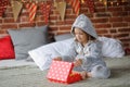 Cute girl 8-9 years, sits on a bed with the Christmas gift in hands.