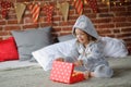 Cute girl 8-9 years, sits on a bed with the Christmas gift in hands.