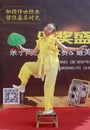 Cute girl in yellow performance fan dance on small bamboo stool