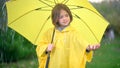 Cute girl in a yellow raincoat with an umbrella in her hands stands in the rain Royalty Free Stock Photo