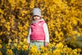 Cute girlon a background field with yellow flowers, happy cute and beautiful kid having fun with yellow flowers in spring in park,
