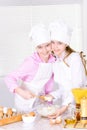 Cute girls in chef`s hats and aprons preparing dough in the kitc