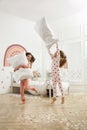 Cute girls in pajamas having pillow fight on bed at home. Happy childhood Royalty Free Stock Photo