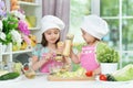 Cute girls preparing delicious fresh salad in kitchen