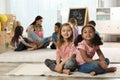 Cute girls sitting on floor while kindergarten teacher reading book to other children Royalty Free Stock Photo