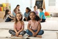 Cute girls sitting on floor while kindergarten teacher reading book to other children Royalty Free Stock Photo
