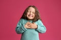 Cute grateful little girl with hands on chest against background