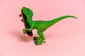 green dinosaur toy with skate isolated on a pink background