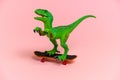 green dinosaur toy with skate isolated on a pink background