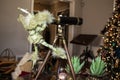 Cute green elf figure with lacy wings peers through antique telescope at Christmas tree - selective focus and bokeh