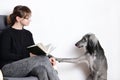 Cute greyhound distract his owner young woman while she reading book. beggar concept