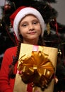 Cute grimacing kid girl in Christmas santa claus hat holding the Royalty Free Stock Photo