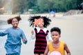 Cute groups of African kids have fun activity together on summer beach blue sea, two girls with black curly hair and boy running Royalty Free Stock Photo